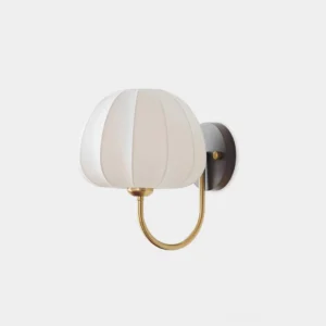 Velum pleated fabric wall sconce with curved gold metal arm and dark mounting base on white studio background