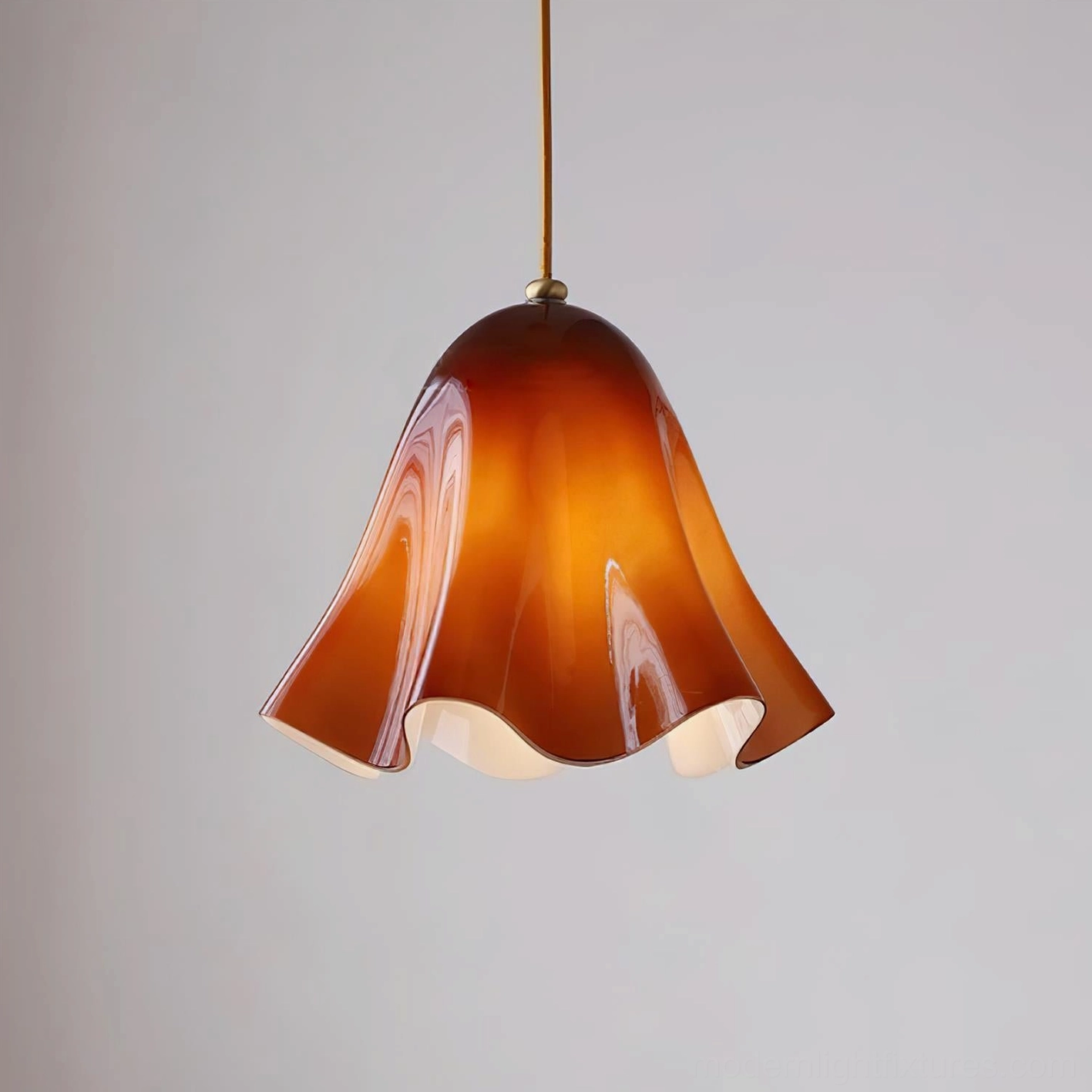 Amber wavy glass Vera pendant light three-quarter view with brass suspension rod on white background