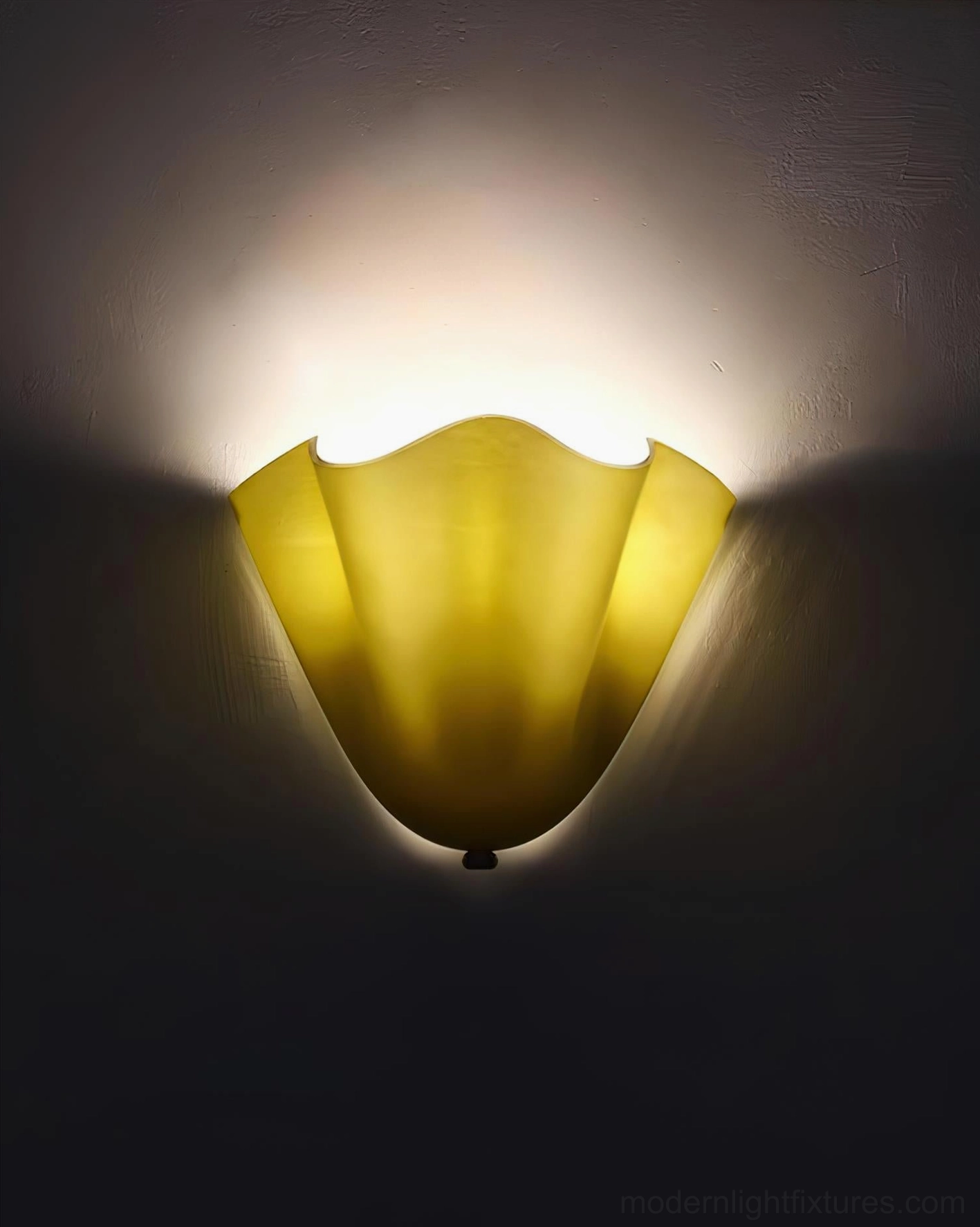 Vera wall sconce glass shade caught mid-angle showing organic petal-like curved form and soft light glow