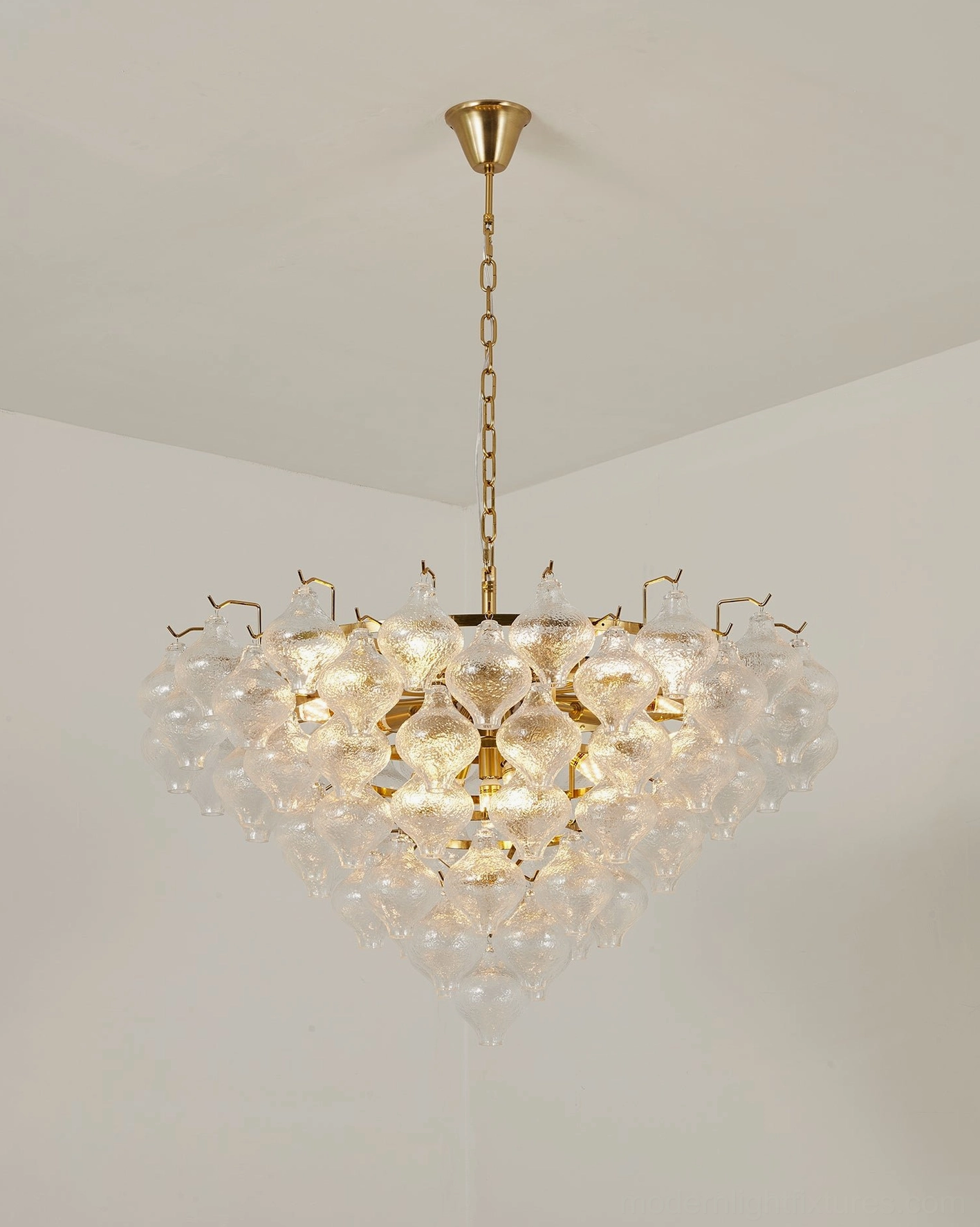Vetrina tiered chandelier with E14 LED candle bulbs installed showing warm white ambient light diffusion through seeded glass