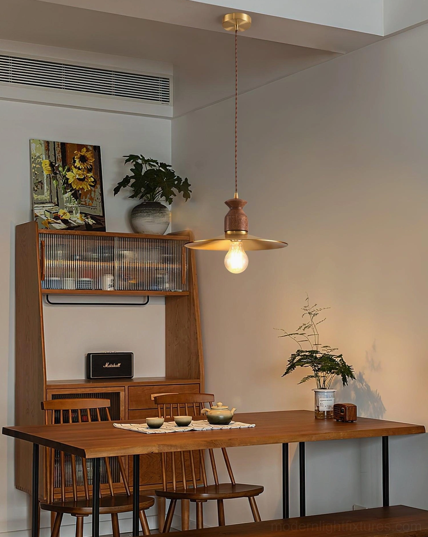 Viana scalloped pendant light three-quarter side view in cozy residential dining room with wooden shelf and wall art