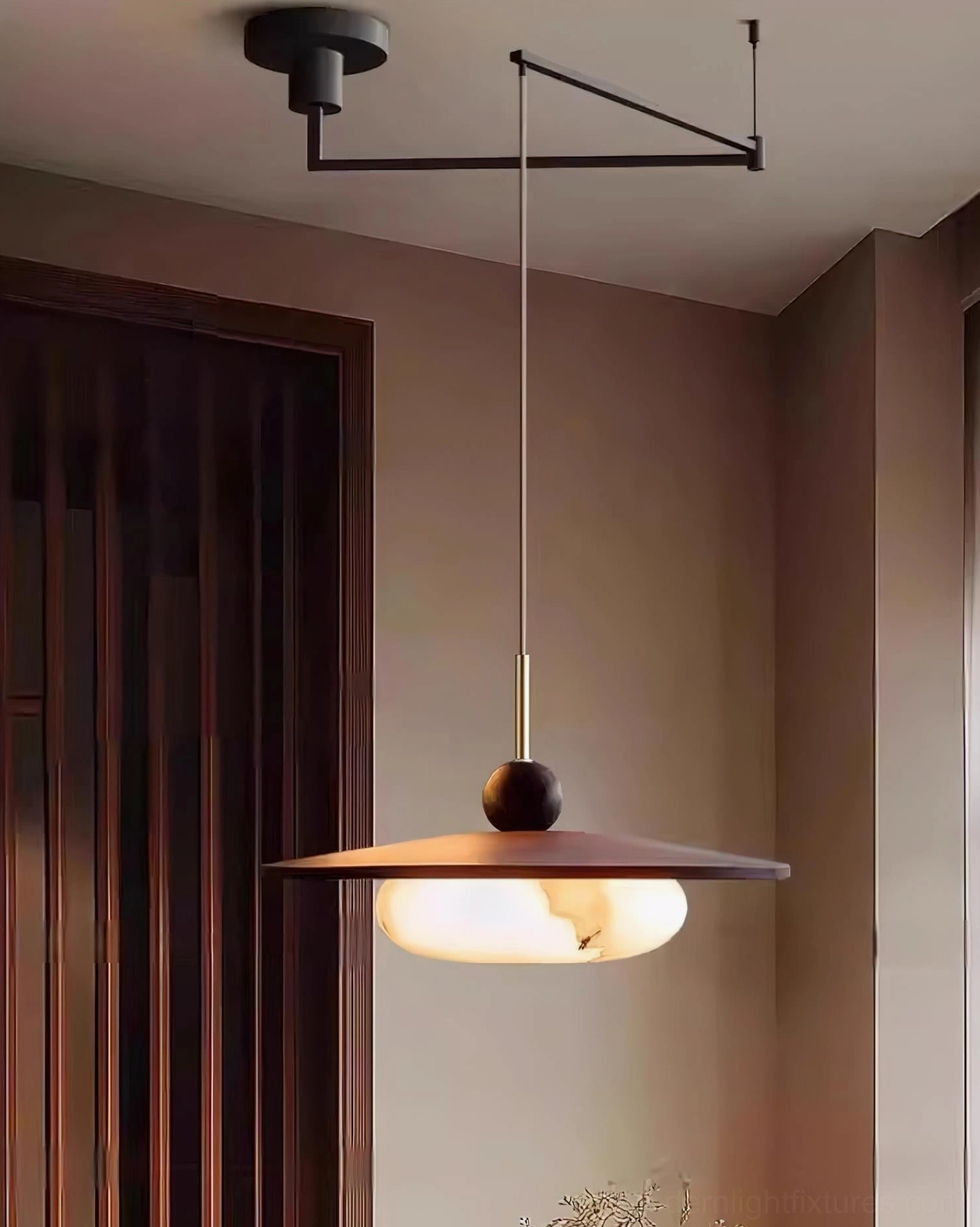 Side profile of swing arm pendant light in dark wood panel entryway with warm ambient glow