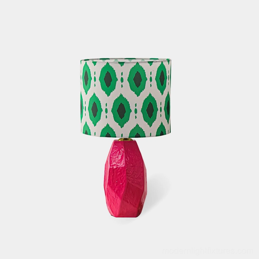 Vico geometric ikat table lamp with pink ceramic base and green patterned shade, front view on white background