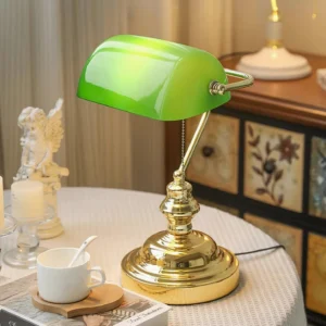 Banker table lamp styled on home tabletop with green glass shade and decorative ornaments