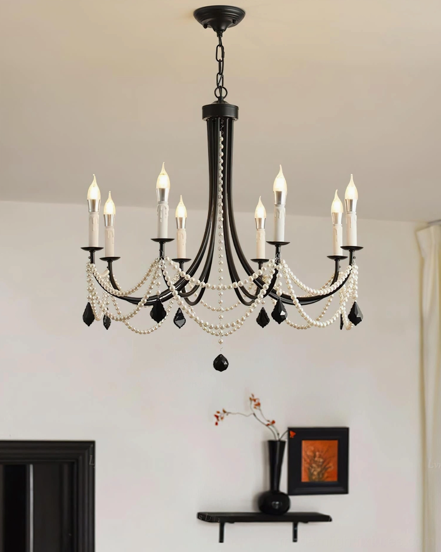 Lit black chandelier with candle-style bulbs in contemporary residential living room with decorative wall shelving