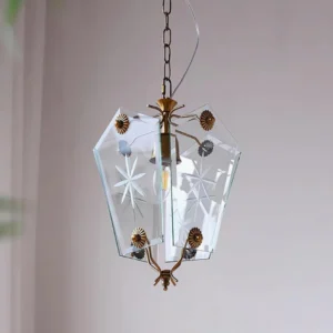 Vintage brass pendant lamp with star-etched clear glass shade angled indoor view with curtains
