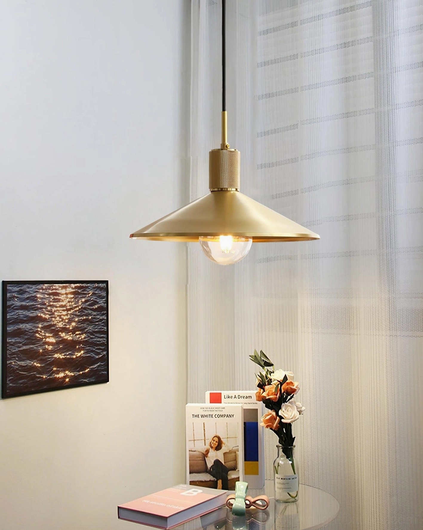 Vintage brass pendant lamp creating warm ambient lighting in cozy living room corner with wall art decor