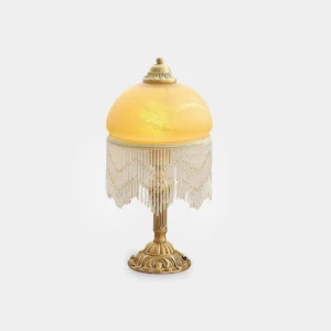 Vintage brass tassel table lamp with frosted amber glass shade and beaded tassel trim on white background - front view