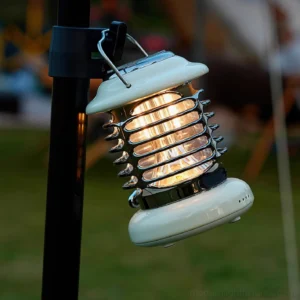 Vintage camp table lamp mounted on outdoor tent pole in natural daylight setting
