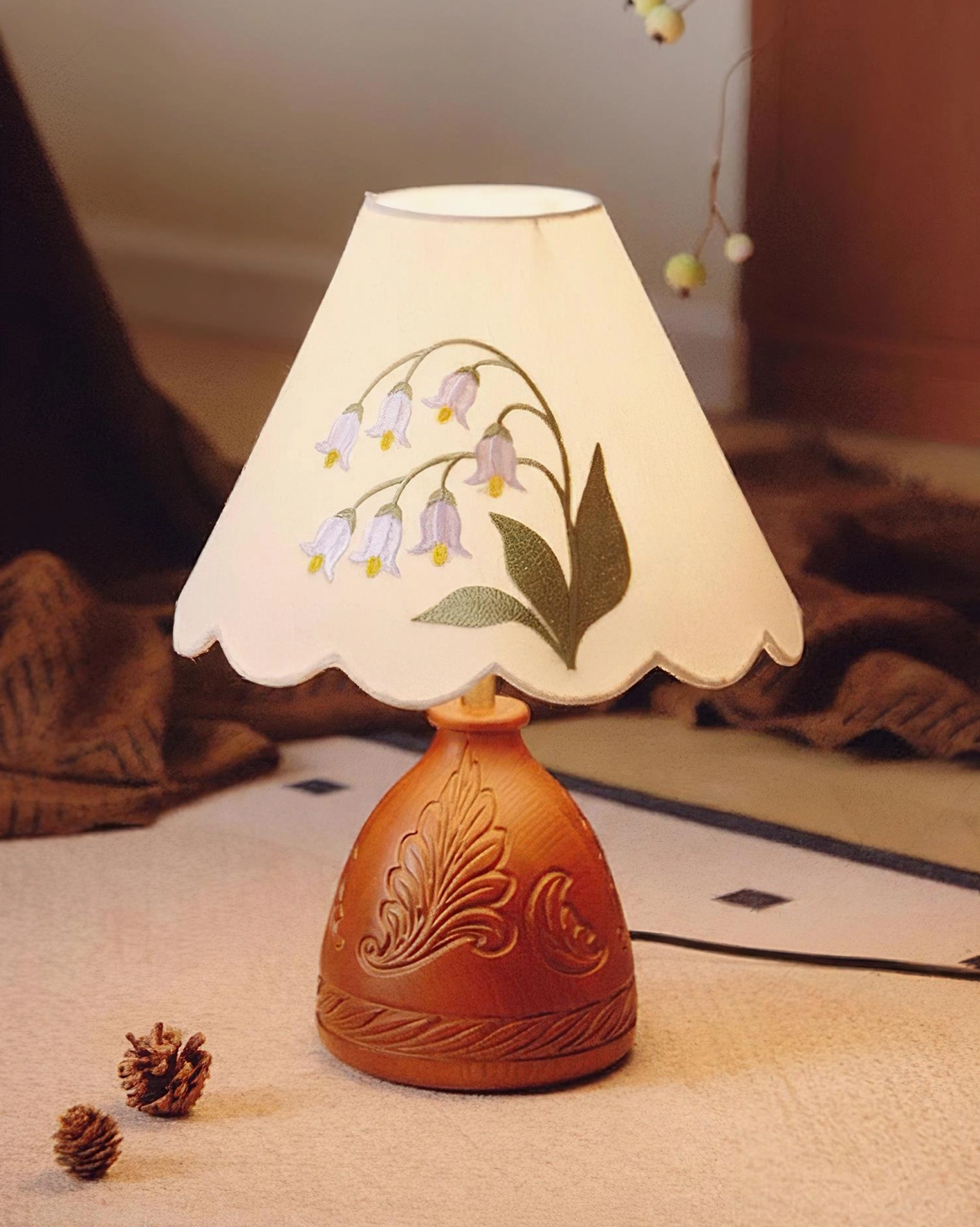 Botanical table lamp with carved wooden base on warm textured surface creating cozy ambiance