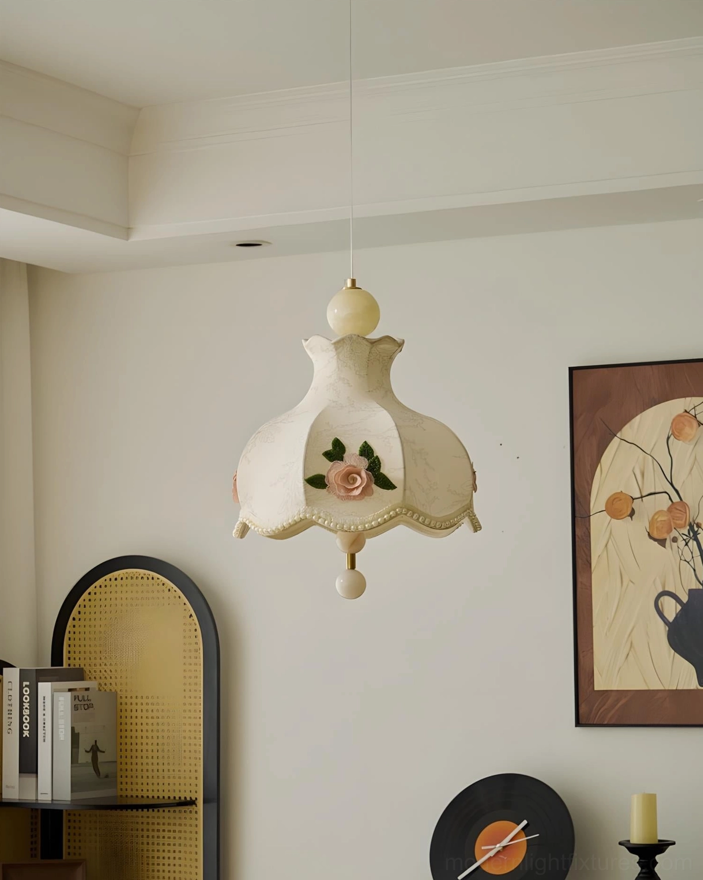 Embroidered fabric pendant fixture mounted above dining table in vintage cottage interior with rattan bookshelf and wall art