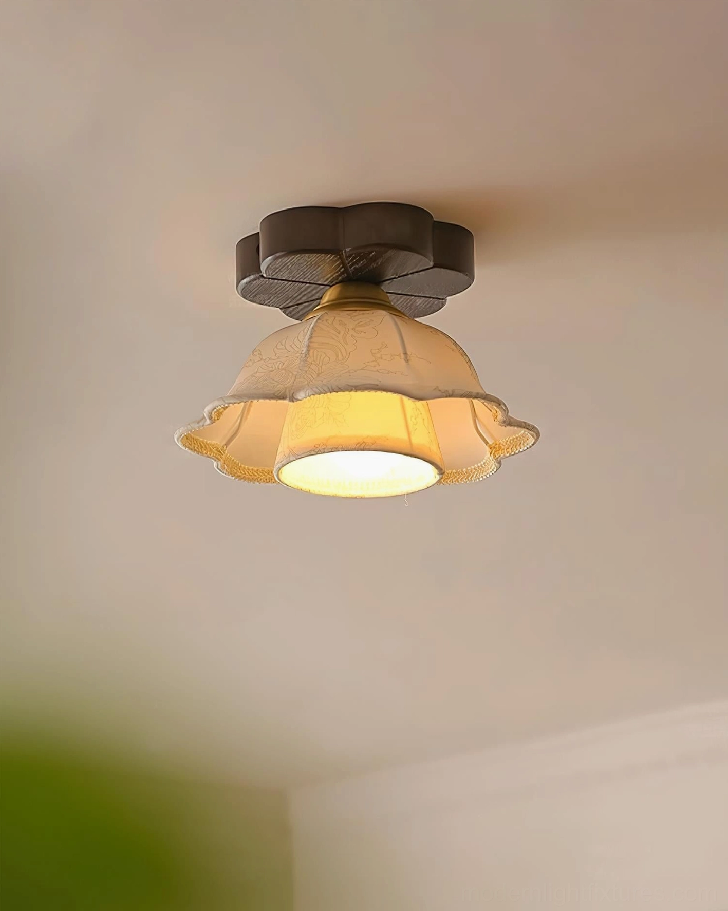 Vintage floral ceiling light installed in cozy cottage room, low-angle view showing warm yellow ambient glow illuminating green wall trim