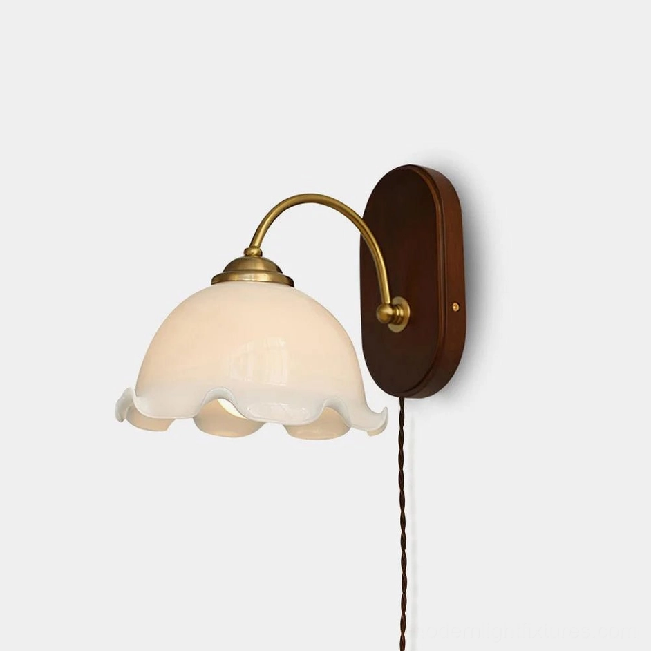 Vintage flower plug-in wall sconce with milk white ruffled glass shade and dark walnut wooden backplate on studio background