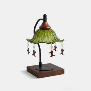 Vintage green ruffled glass candle warmer lamp with black metal arm and walnut wood base, studio front view with white background