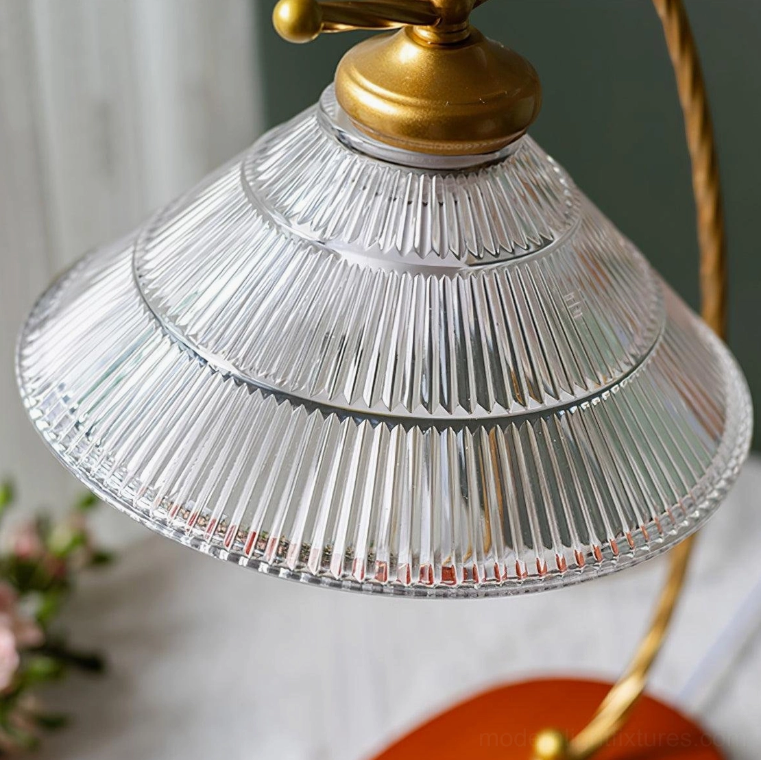 Close-up detail of vintage table lamp's tiered fluted transparent glass shade with brass-gold top fixture and textured surface