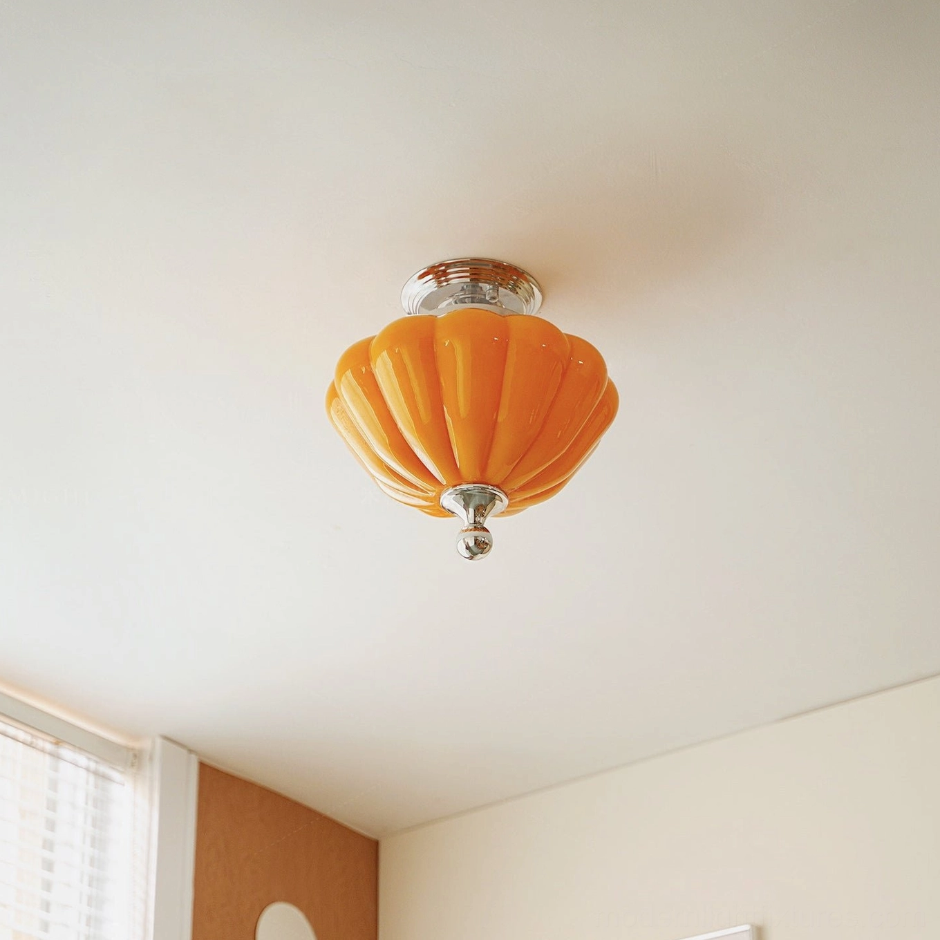 Residential interior corner view of ribbed orange glass semi-flush ceiling light with vintage lantern chrome hardware design