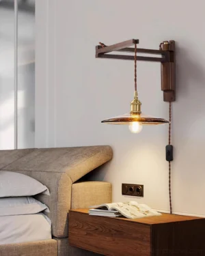 Plug-in vintage wall sconce with dark walnut wood bracket installed beside bedroom nightstand, warm ambient glow