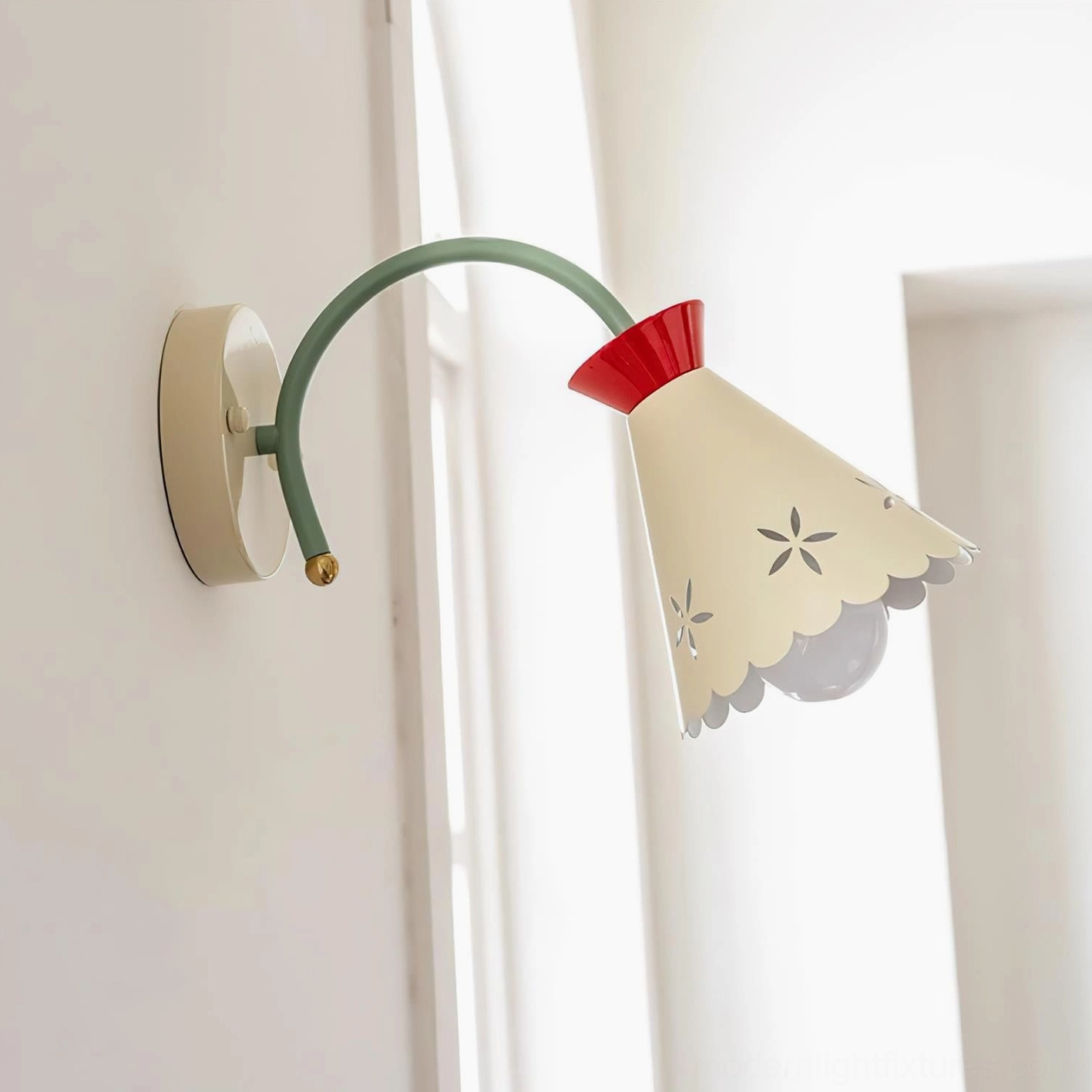 Cream pastel wall sconce with curved green arm mounted on neutral wall - three-quarter view