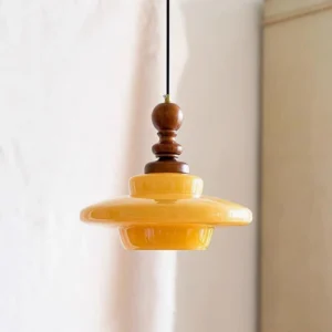 Mid-century modern pendant lamp with golden amber glass shade and walnut wood hardware, indoor three-quarter angle view