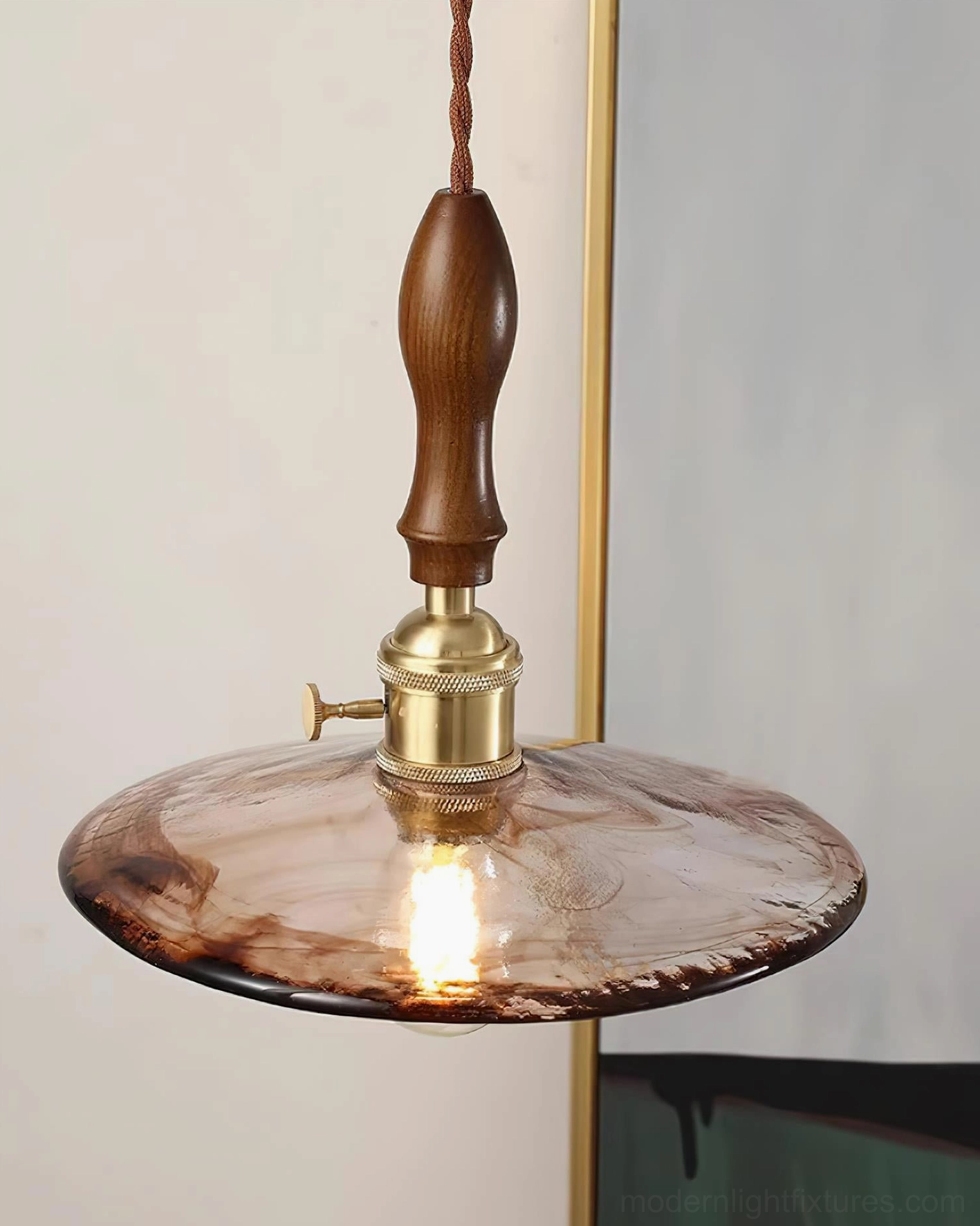 Close-up detail of vintage pendant light marbled amber glass shade with polished brass fixture