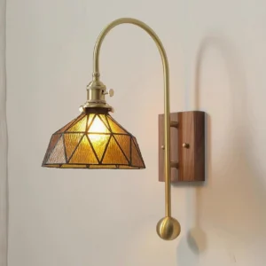 Wall-mounted brass sconce with conical amber stained glass shade and spherical counterweight