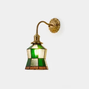 Vintage stained glass wall sconce with emerald green and amber glass panels and ornate brass wall mount, shown from front three-quarter angle on white background