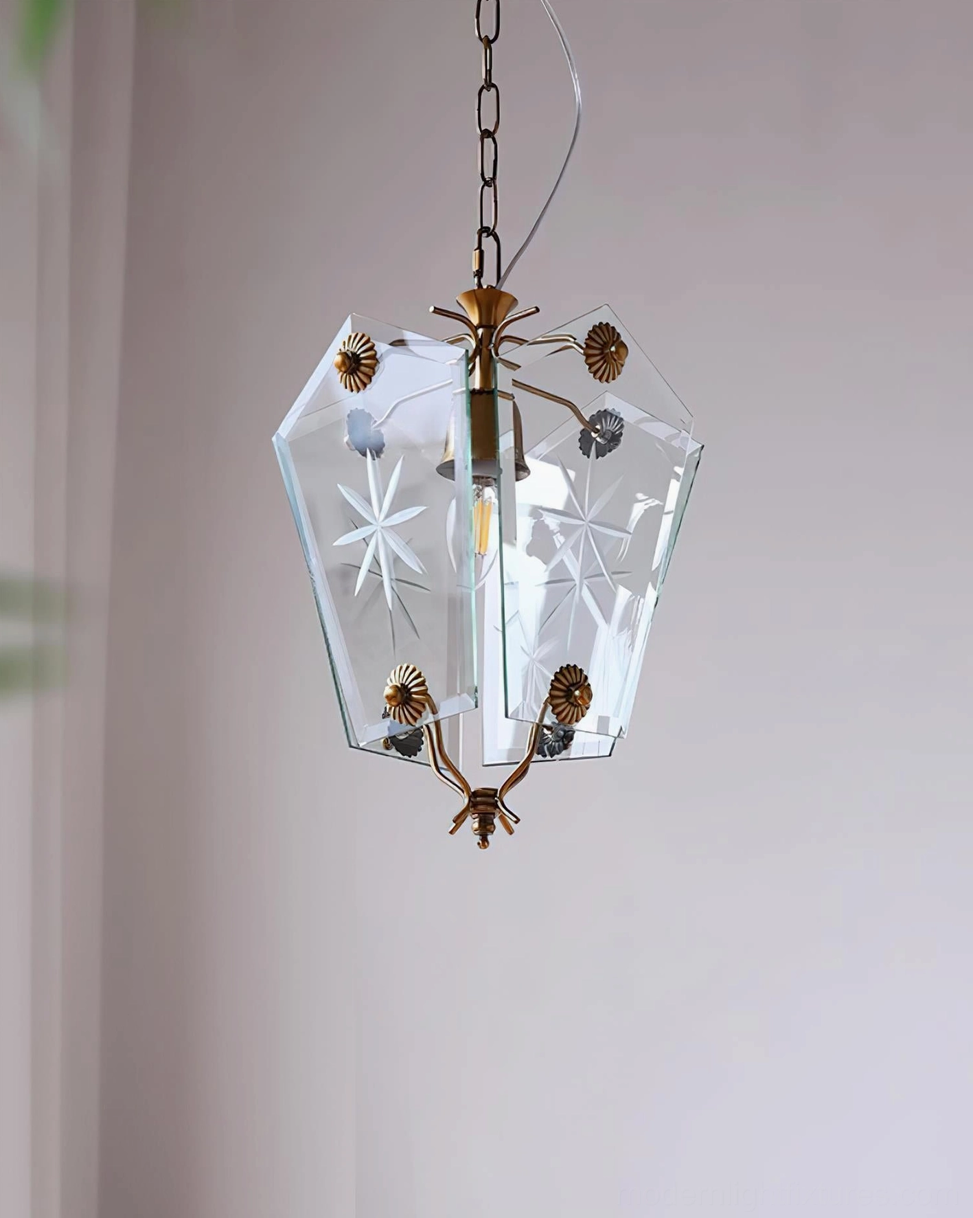 Side angle view vintage star-etched glass pendant light with brass accents and curtained wall