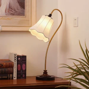 Retro fabric shade table lamp on home study desk with books and wall art - warm lighting ambiance