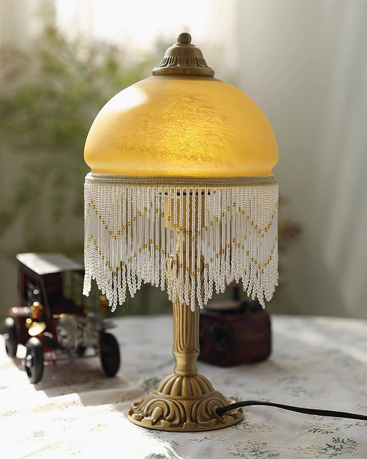 Vintage brass tassel table lamp with floral tablecloth backdrop and soft natural warm daylight illumination