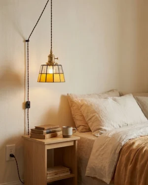 Plug-in amber stained glass pendant light hanging over bedroom bedside nightstand with warm vintage farmhouse lighting creating cozy ambiance