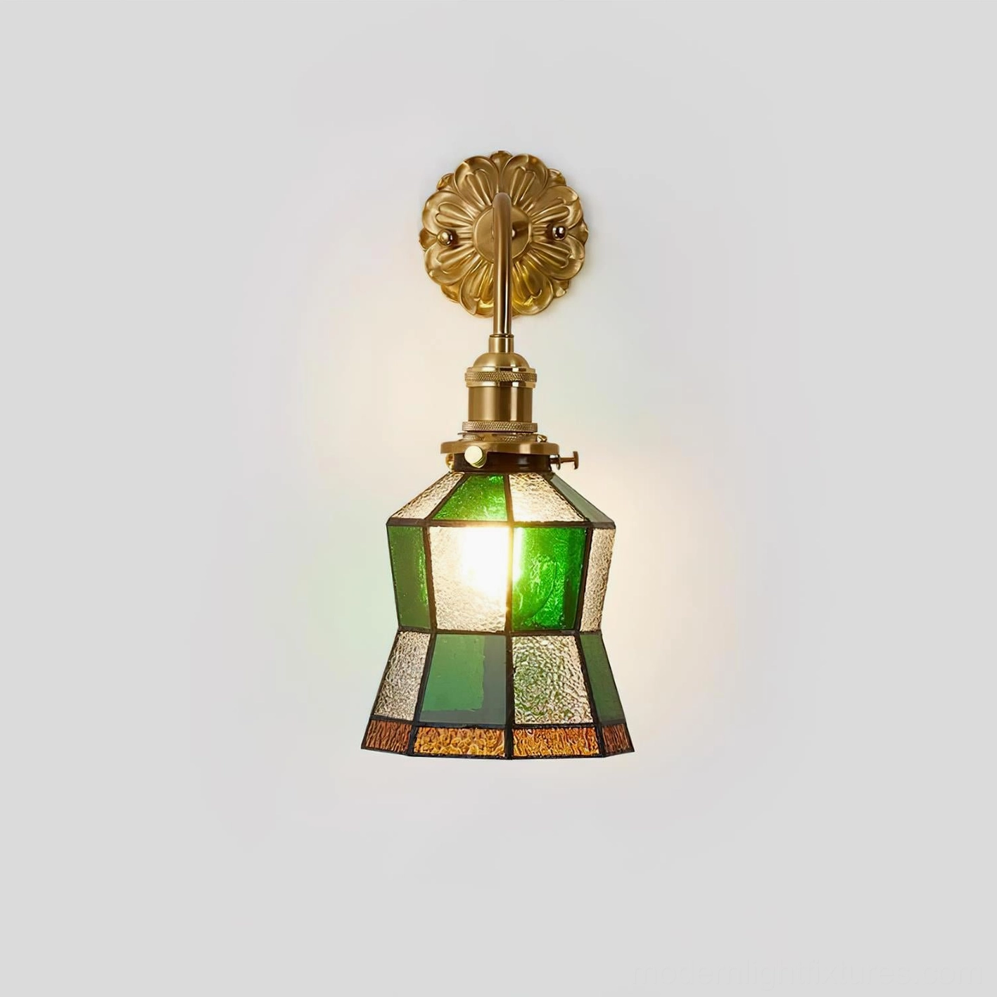 Vintage stained glass wall sconce with illuminated central bulb and antique brass hardware finish, direct front view on gray background