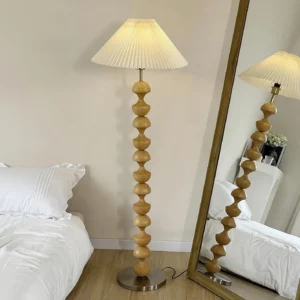Natural light wood beaded floor lamp in bedroom setting with full-length mirror, light yellow wood grain pole and silver metal base, ambient lighting