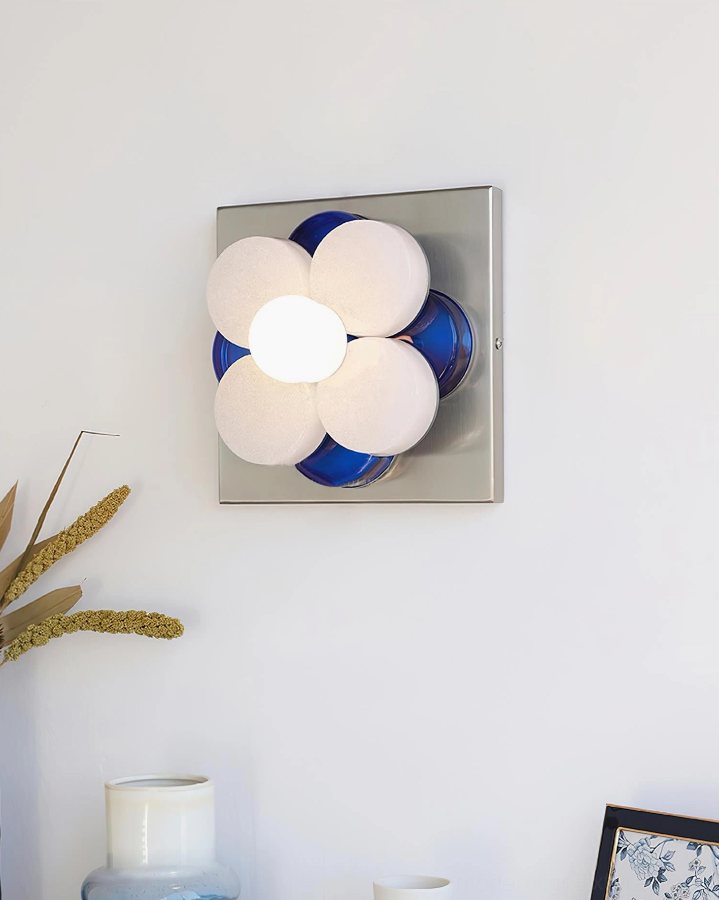 Violetta wall sconce installation showing vertical mounting on wall with blue frosted petals and industrial chrome base