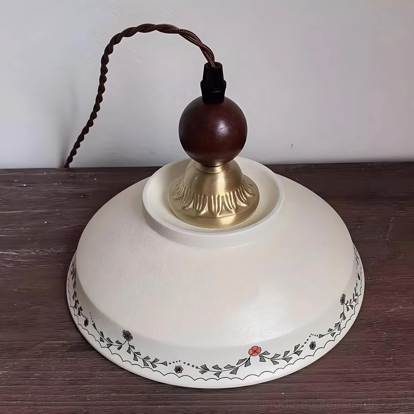 Virella pendant light with ceramic botanical shade, brass metal base, and natural wood sphere accent, artistic detail view