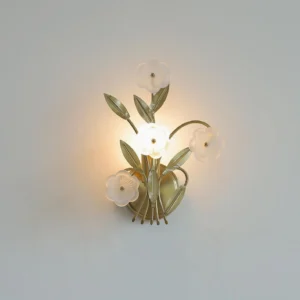 Virella botanical wall sconce lit with warm amber glow, close-up detail of frosted glass flowers and metal stems