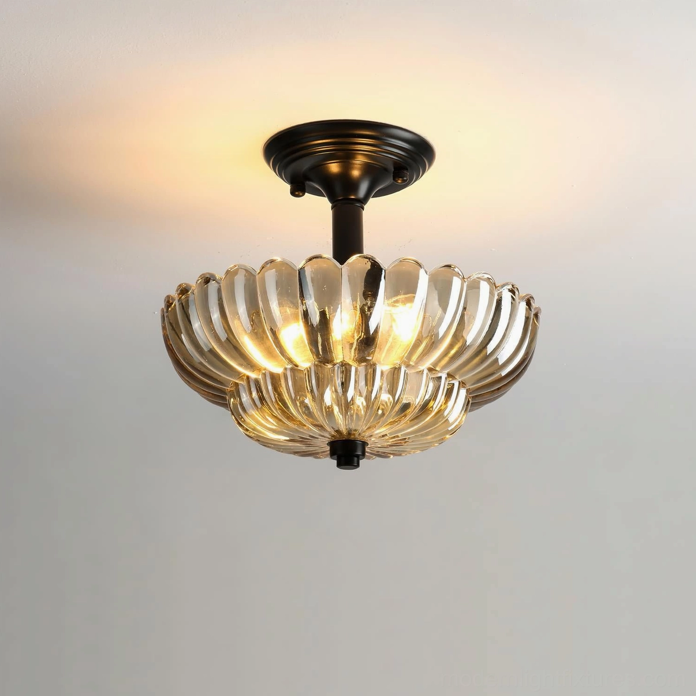 Virenza modern ceiling lamp illuminated, showing warm amber glow from scalloped glass petal design, close-up detail view