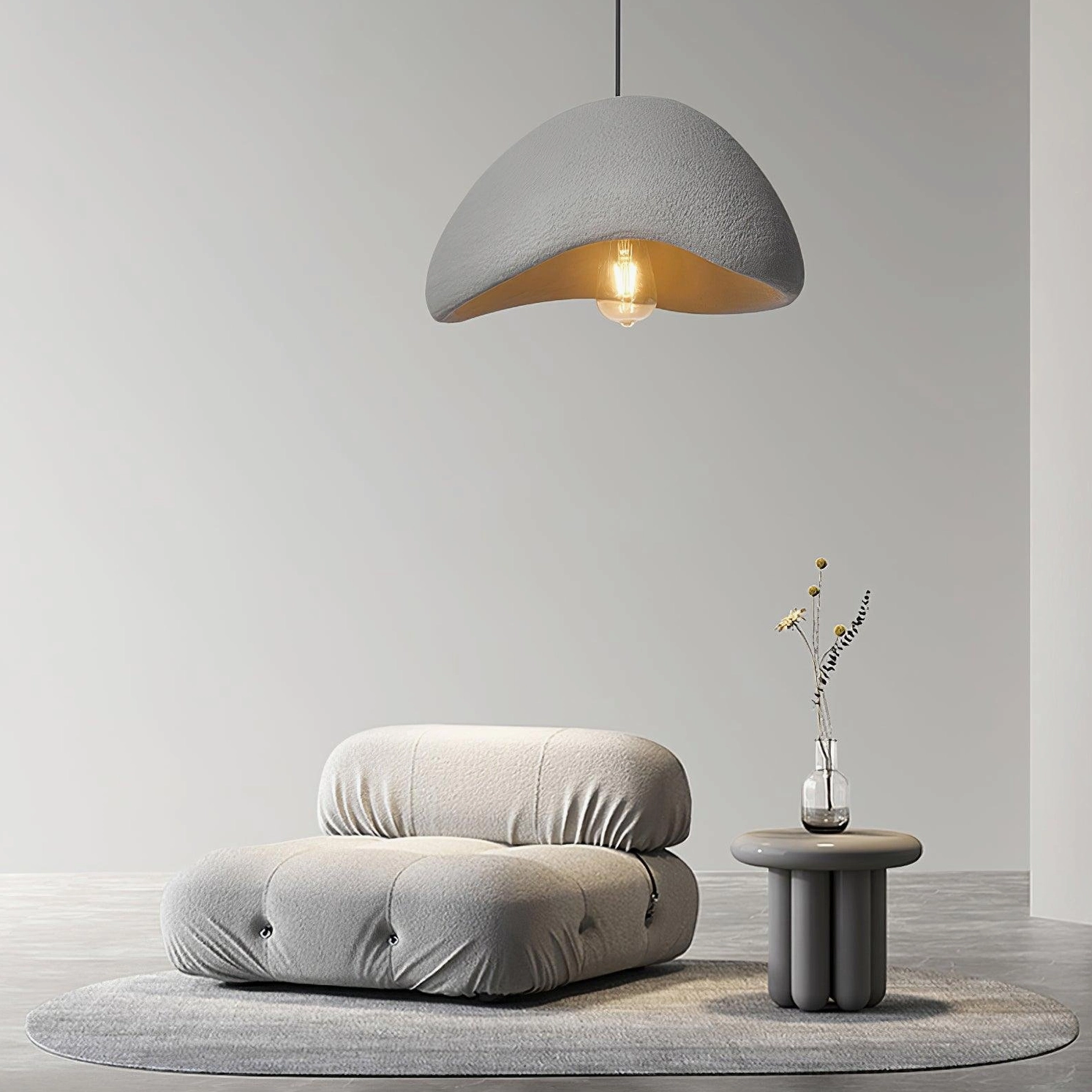 Single wabi-sabi pendant light with grey half-dome showing exposed warm bulb in minimalist living space