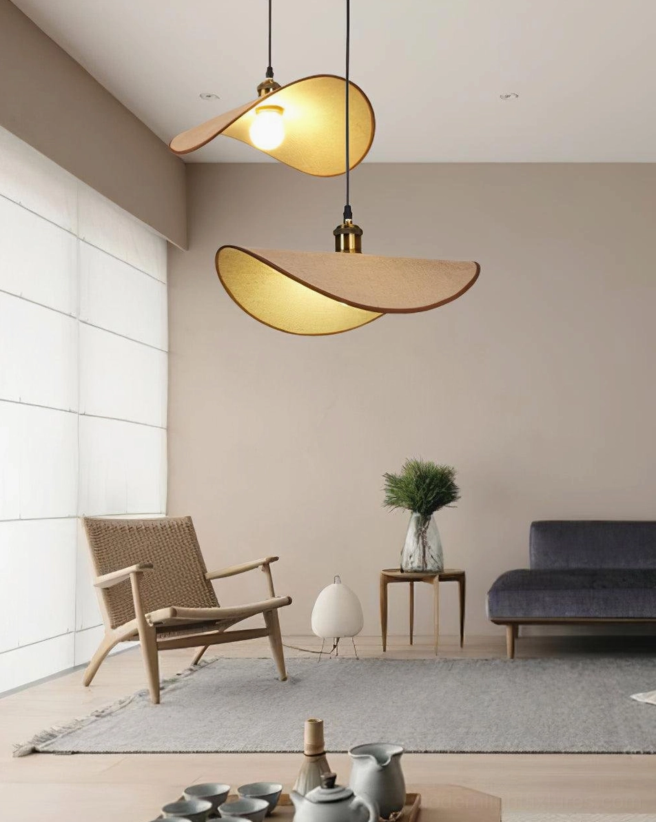 Two pendant lamps in low-angle living room view with minimalist furniture, potted plant, and soft natural light
