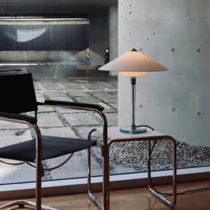 Bauhaus style table lamp three-quarter view on industrial concrete patio with cantilever leather chair, modern interior design
