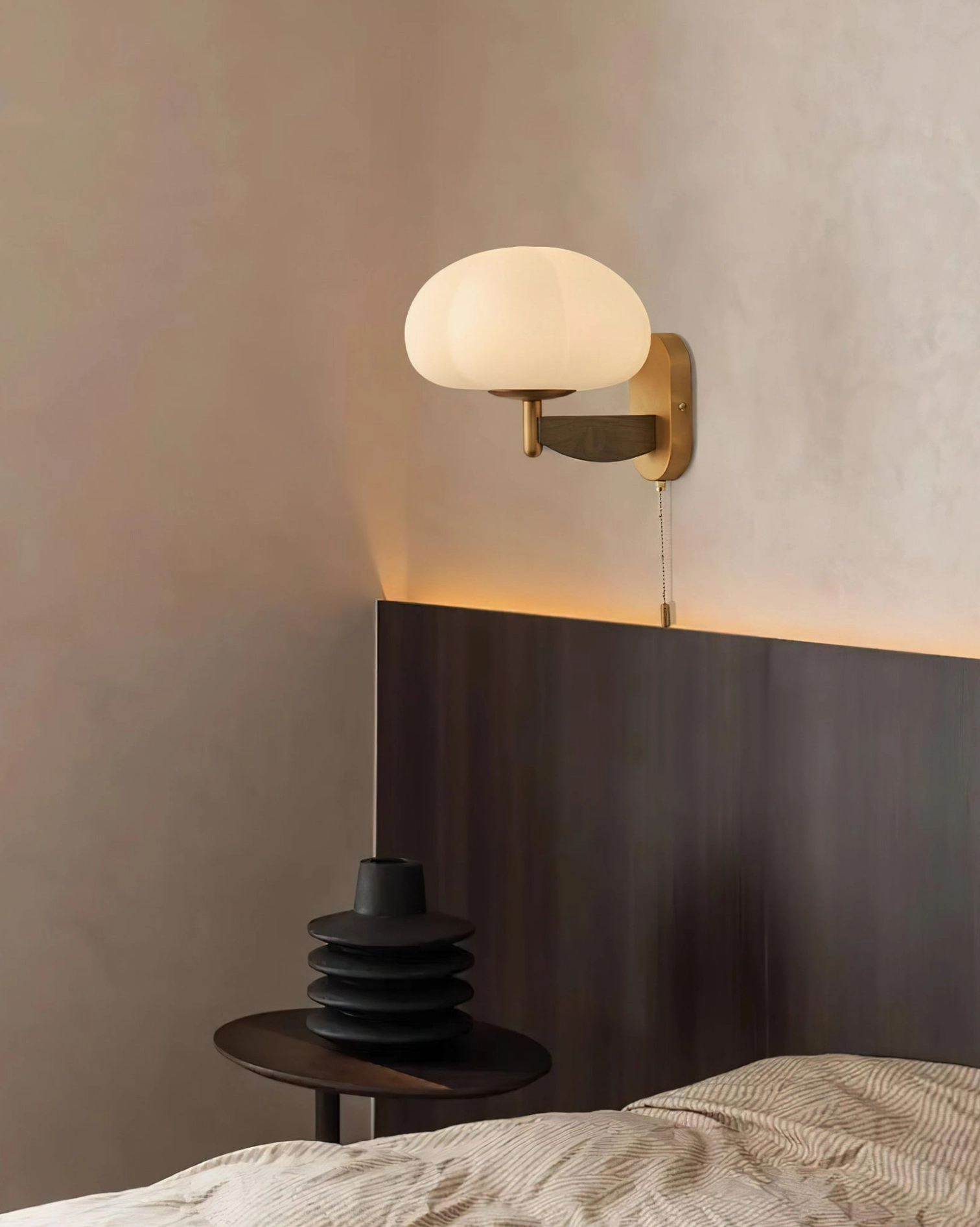 Modern rustic wall sconce above dark wood headboard in bedroom with muted warm tones