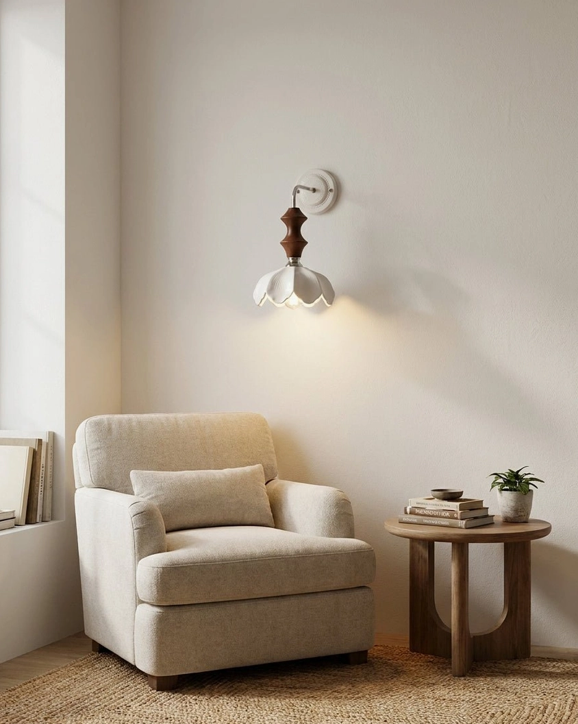 Contemporary ceramic wall sconce illuminating reading nook with linen armchair and wooden side table