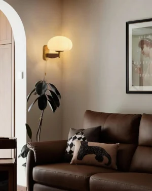 Vintage-inspired wall sconce lighting in retro living room setting with warm glow above brown leather sofa