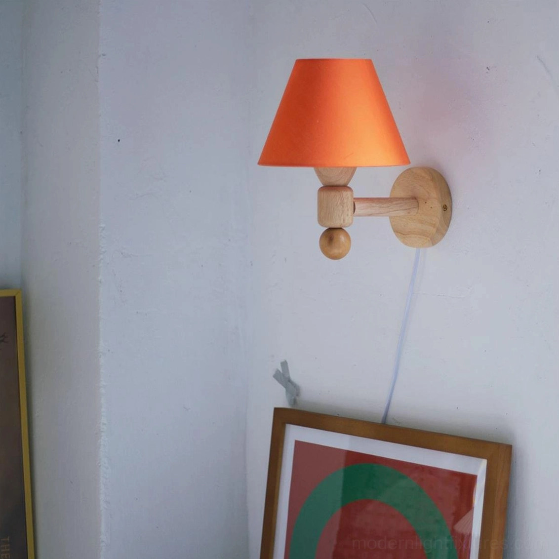 Side profile view of hardwired wall sconce showing sculptural wooden bracket with decorative sphere detail and orange fabric shade