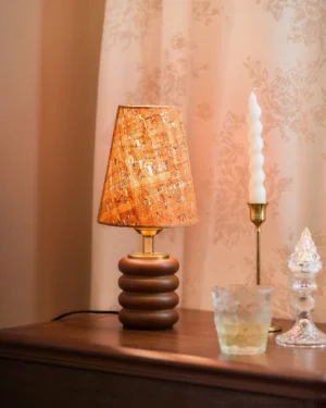 Warm 3000K walnut table lamp with cork shade on bedroom nightstand beside brass candle holder and glass