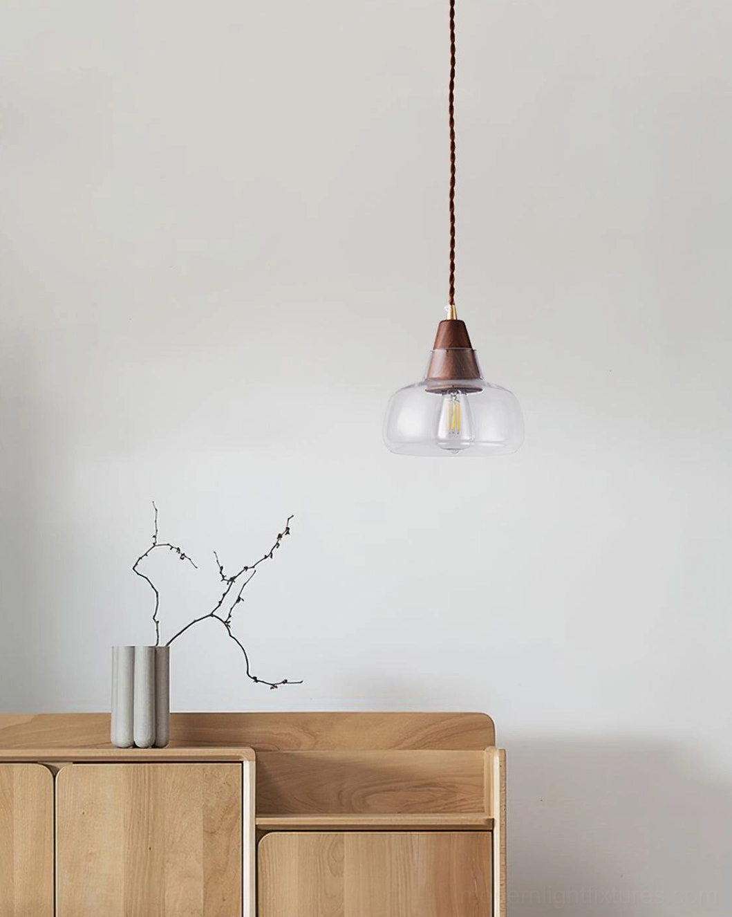 Modern walnut wood glass pendant light above minimalist wooden console table with branch decor, contemporary hallway
