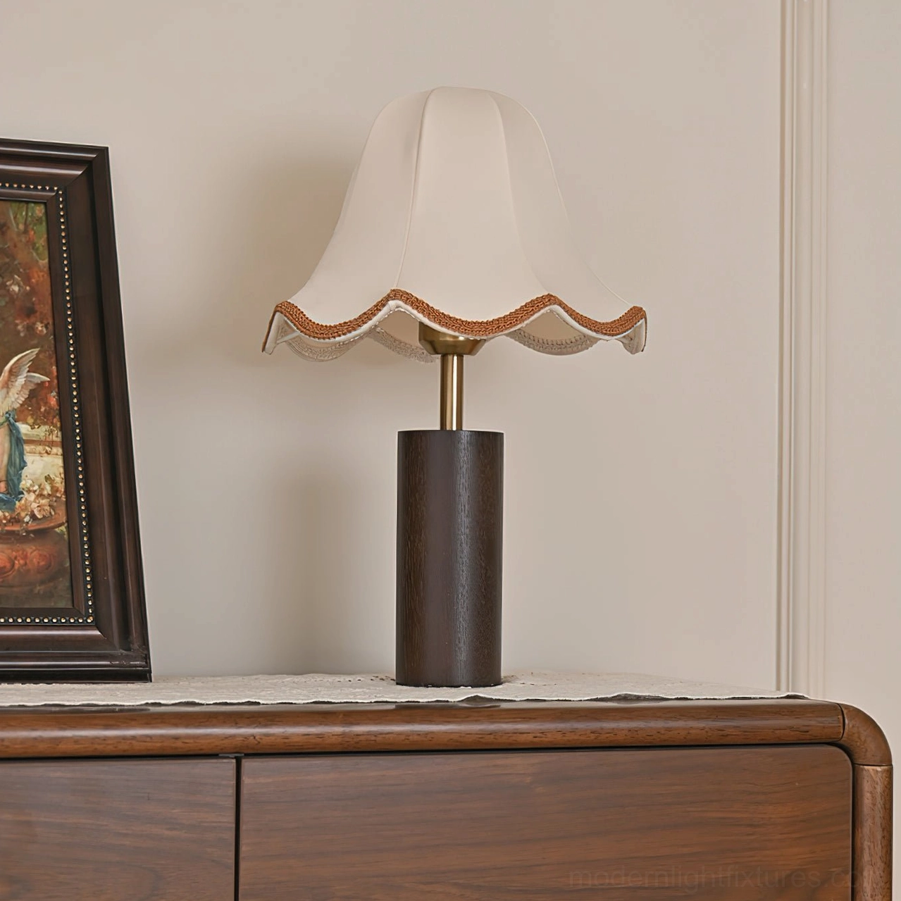 Unlit walnut table lamp with scalloped fabric shade on wooden dresser in home interior setting