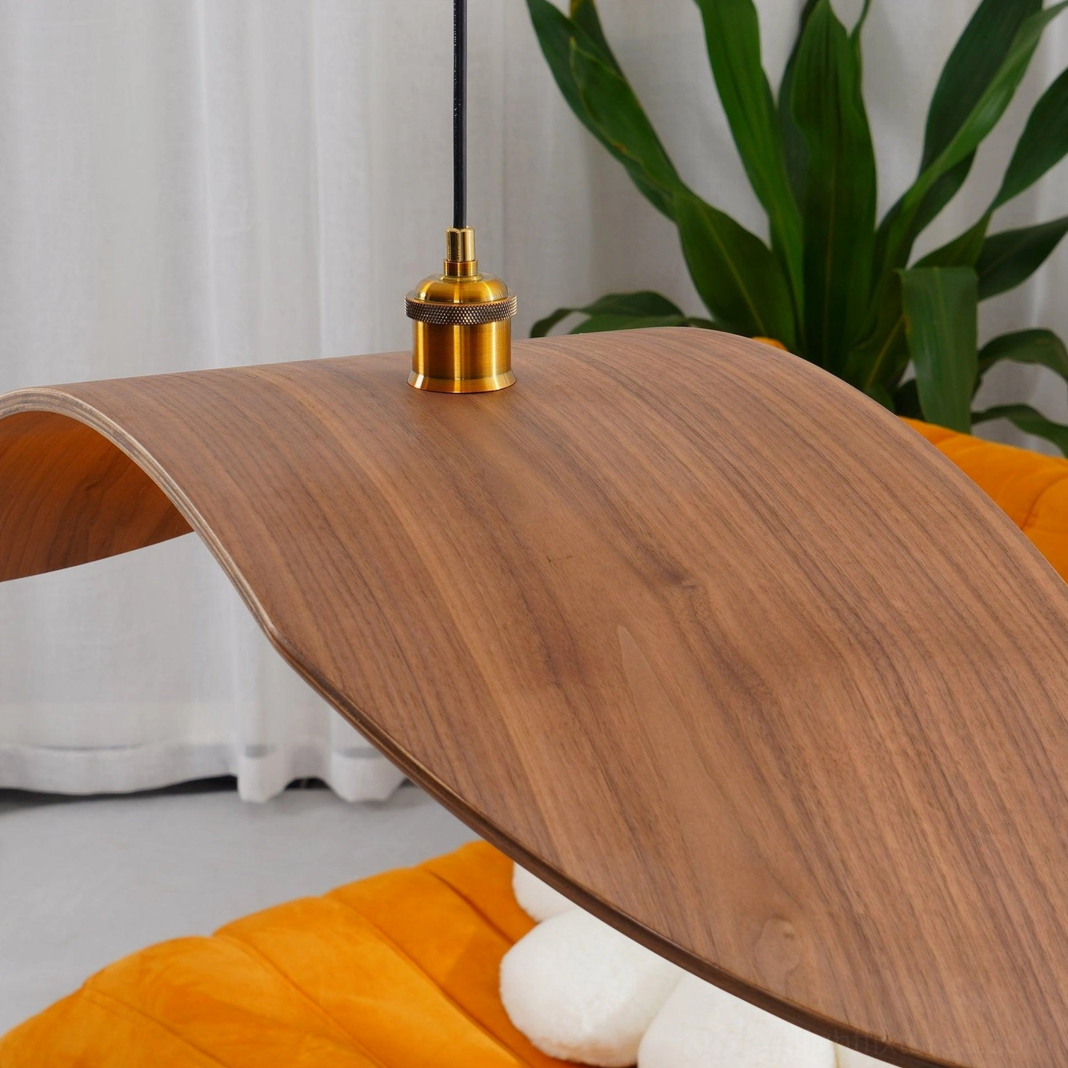 Close-up detail of walnut wood leaf pendant lamp shade and brass mounting fixture with natural wood grain texture