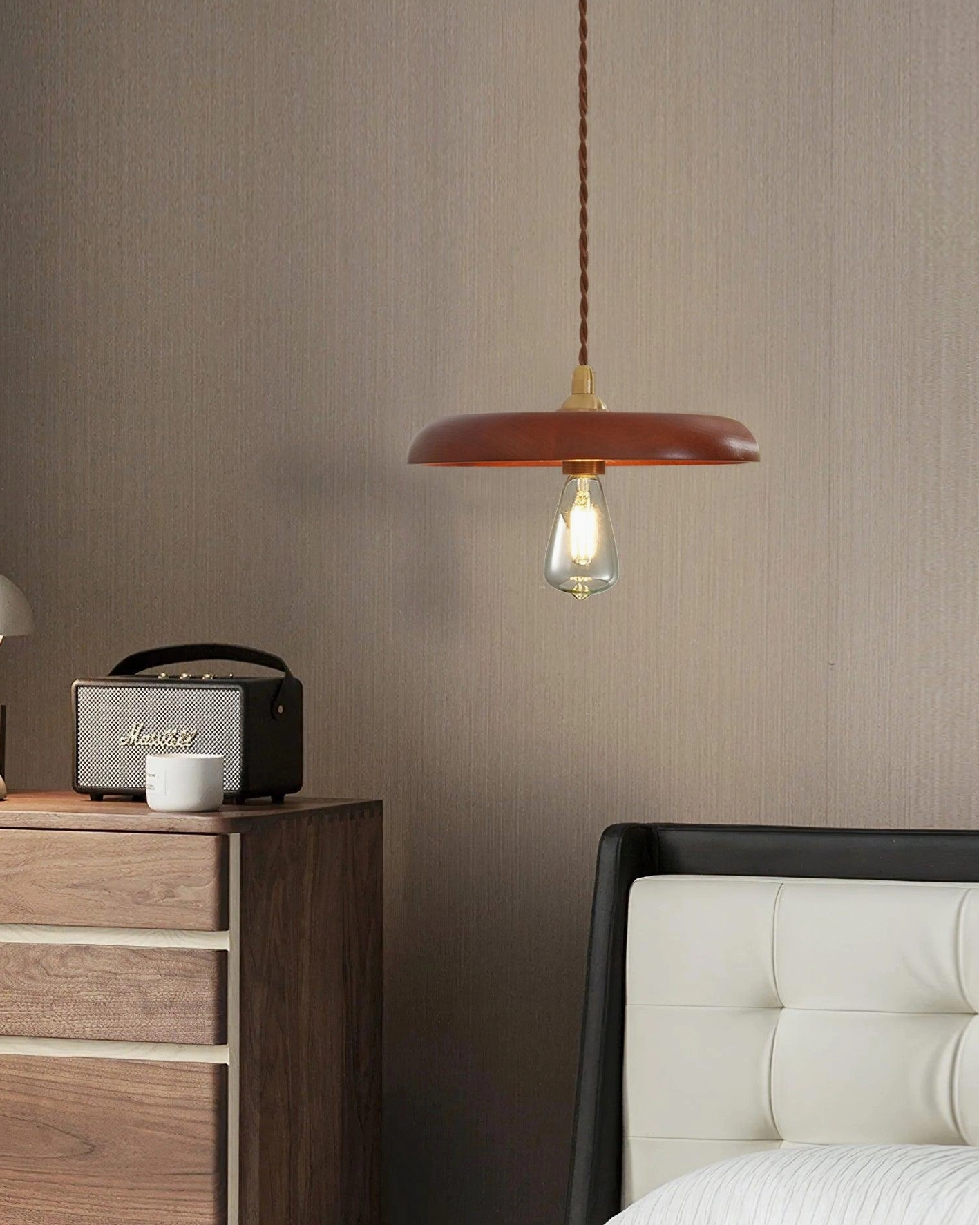 Minimalist wooden pendant light in modern bedroom setting above nightstand with warm ambient glow