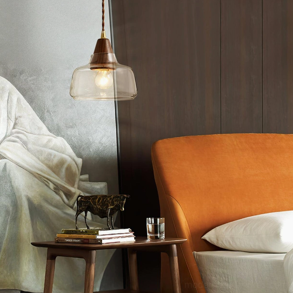 Walnut wood glass pendant lamp in cozy living lounge with dark wood wall and orange accent chair, warm ambient lighting