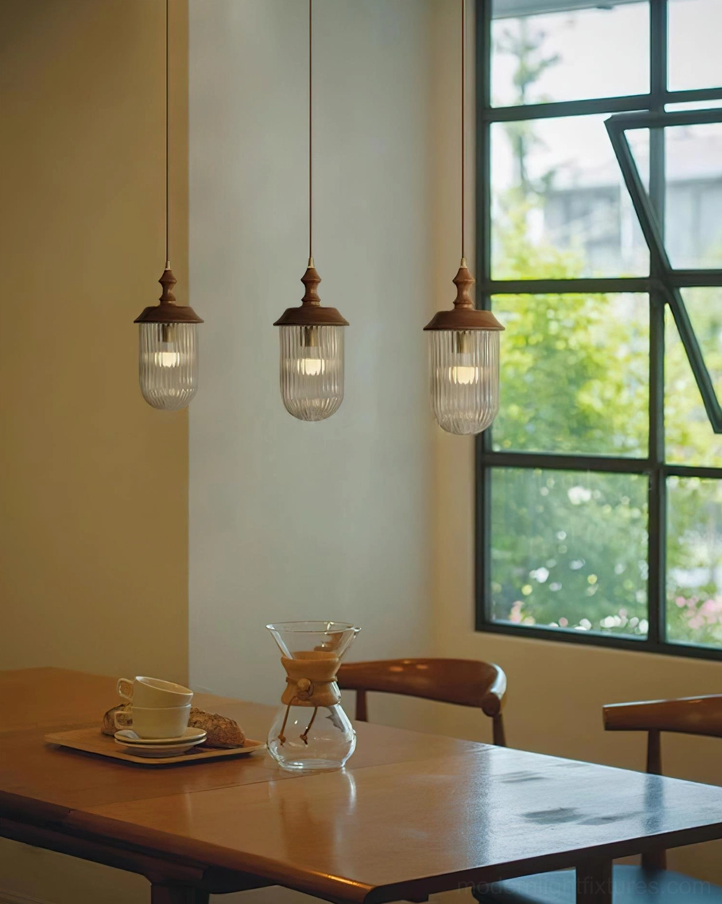 Trio of walnut wood pendant lamps with clear fluted glass shades in family dining room wide view